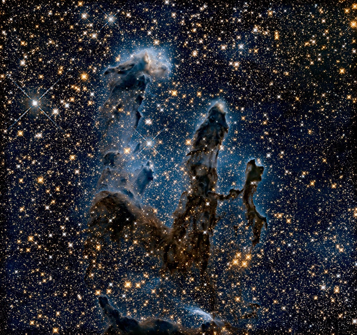 Tall columns of gas and dust in the Eagle Nebula stand against a dense field of stars.